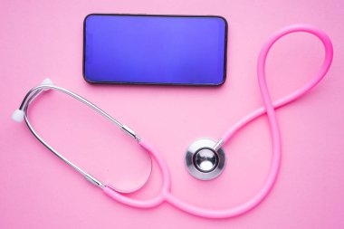 Kadın sağlık hizmetleri konsepti teknolojisi. Pembe bir steteskop ve pembe arka planda bir akıllı telefon. Peyzaj yönelimi.