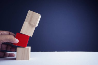 Mali risk değerlendirmesi, risk ödülü ve portföy risk yönetimi konsepti. Kırmızıyla işaretlenmiş dört tahta küp. Bir küpü hareket ettirmeye çalışan bir el. Boşluğu kopyala.