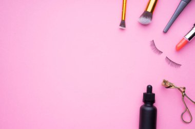 Pembe arka planda kozmetik ürünlerinin yaratıcı düzenlenmesi.