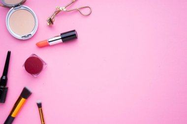 Pembe arka planda kozmetik ürünlerinin yaratıcı düzenlenmesi.