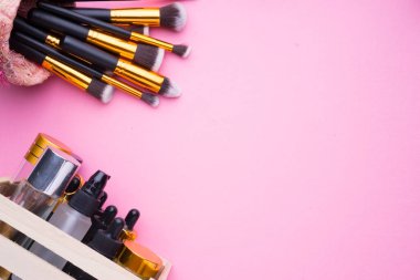 Pembe arka planda kozmetik ürünlerinin yaratıcı düzenlenmesi.