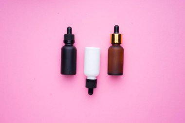 Pembe arka planda kozmetik ürünlerinin yaratıcı düzenlenmesi.