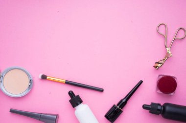 Pembe arka planda kozmetik ürünlerinin yaratıcı düzenlenmesi.