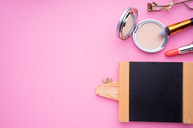 Pembe arka planda kozmetik ürünlerinin yaratıcı düzenlenmesi.