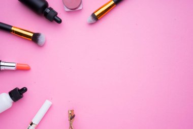 Pembe arka planda kozmetik ürünlerinin yaratıcı düzenlenmesi.
