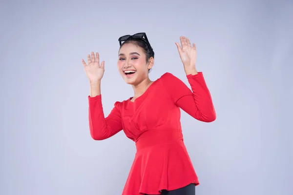 stock image An attractive woman wearing casual red attire with gestures and poses towards copyspace isolated on grey. Good for technology, transportation, business or finance concept