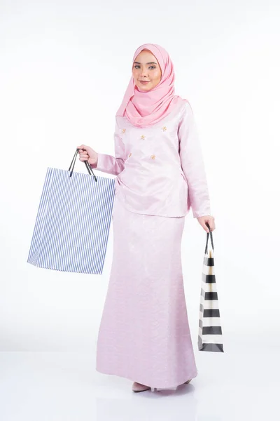 白い背景に隔離されたショッピングバッグを運ぶアジアの伝統的なドレスの美しいイスラム教徒の女性モデル イドゥル フィトリのお祝いの準備ショッピングコンセプト 全長像 — ストック写真