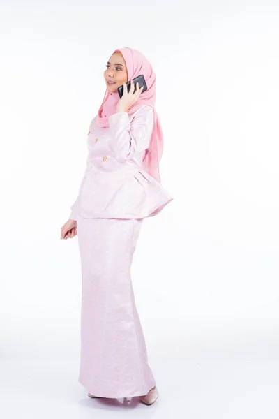 一位有魅力的穆斯林女士穿着传统服饰 头戴头巾 用她的智能手机自拍 用白色背景打独立电话 — 图库照片