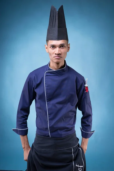 Mavi Üniformalı Siyah Önlüklü Mavi Arka Planda Siyah Şapkalı Asyalı — Stok fotoğraf