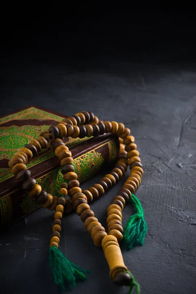 Faith in Islam concept. The Islamic holy book Quran or Kuran with rosary beads or tasbih on dark background.