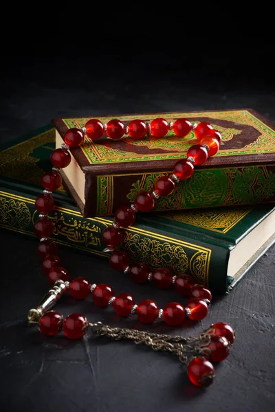 Faith in Islam concept. The Islamic holy book Quran or Kuran with rosary beads or tasbih on dark background.