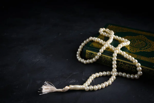 Faith in Islam concept. The Islamic holy book Quran or Kuran with rosary beads or tasbih on dark background.