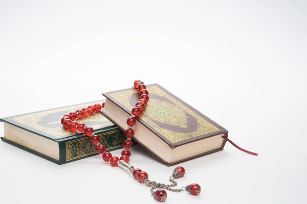 Faith in Islam concept. The Islamic holy book Quran or Kuran with rosary beads or tasbih isolated on white background.