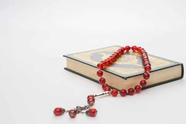 Faith in Islam concept. The Islamic holy book Quran or Kuran with rosary beads or tasbih isolated on white background.