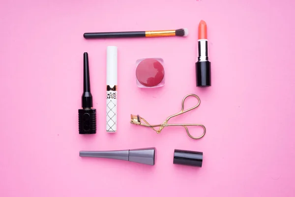 Creative arrangement of cosmetics products on pink background.