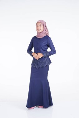 Koyu mavi, tesettürlü bir modern kebaya giyen güzel bir Müslüman kadın model. Beyaz arka planda izole edilmiş Asyalı Müslüman geleneksel bir elbise. Eidul Fitri moda ve yaşam tarzı portresi konsepti.