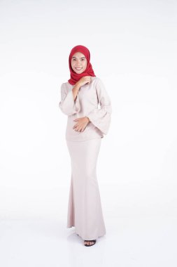 Beyaz arka planda izole edilmiş Asyalı Müslüman geleneksel bir elbise olan kırmızı tesettürlü krem renkli bir modern kebaya giyen çekici Müslüman kadın manken. Eidul Fitri moda ve yaşam tarzı portresi konsepti.