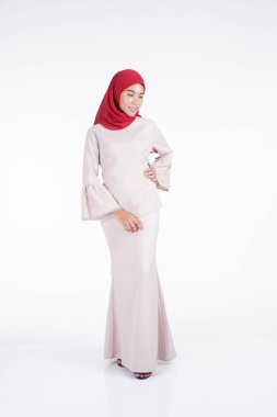 Beyaz arka planda izole edilmiş Asyalı Müslüman geleneksel bir elbise olan kırmızı tesettürlü krem renkli bir modern kebaya giyen çekici Müslüman kadın manken. Eidul Fitri moda ve yaşam tarzı portresi konsepti.