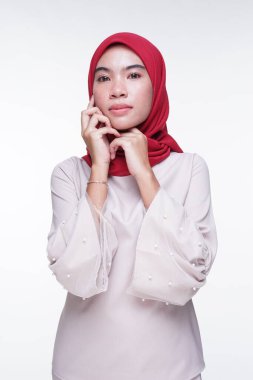 Beyaz arka planda izole edilmiş Asyalı Müslüman geleneksel bir elbise olan kırmızı tesettürlü, krem renkli modern kebaya giymiş güzel bir Müslüman kadın modelin yakın çekimi. Eidul Fitri moda ve yaşam tarzı portresi konsepti.