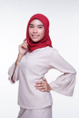 Beyaz arka planda izole edilmiş Asyalı Müslüman geleneksel bir elbise olan kırmızı tesettürlü, krem renkli modern kebaya giymiş güzel bir Müslüman kadın modelin yakın çekimi. Eidul Fitri moda ve yaşam tarzı portresi konsepti.