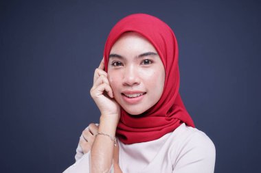 Krem rengi, modern kebaya rengi kırmızı tesettürlü güzel bir Müslüman kadın modelin portresi. Gri arka planda izole edilmiş Asyalı Müslüman geleneksel bir elbise. Eidul Fitri moda ve yaşam tarzı portresi konsepti.