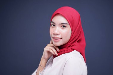 Krem rengi, modern kebaya rengi kırmızı tesettürlü güzel bir Müslüman kadın modelin portresi. Gri arka planda izole edilmiş Asyalı Müslüman geleneksel bir elbise. Eidul Fitri moda ve yaşam tarzı portresi konsepti.