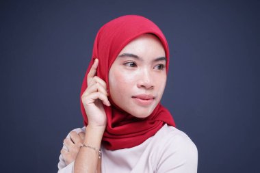 Krem rengi, modern kebaya rengi kırmızı tesettürlü güzel bir Müslüman kadın modelin portresi. Gri arka planda izole edilmiş Asyalı Müslüman geleneksel bir elbise. Eidul Fitri moda ve yaşam tarzı portresi konsepti.