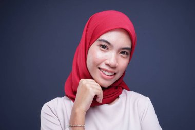 Headshot of a beautiful Muslim female model in a cream modern kebaya with red hijab, an Asian Muslim traditional dress isolated on grey background. Eidul fitri fashion and lifestyle portrait concept.