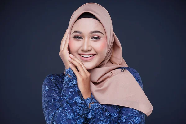 Closeup of a beautiful female Muslim model wearing dark blue modern kurung with hijab, a modern urban lifestyle apparel for Muslim women isolated on grey background. Beauty and hijab fashion concept.