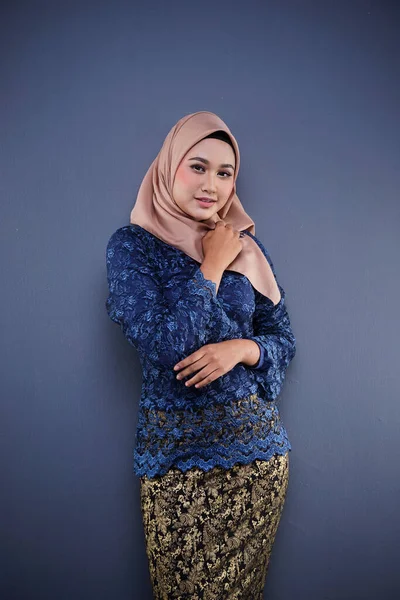 Attractive female Muslim model wearing dark blue modern kurung with hijab, a modern urban lifestyle apparel for Muslim women isolated on grey background. Beauty and hijab fashion concept.