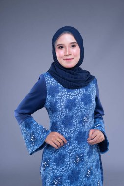 Çeşitli pozlarda güzel bir Müslüman kadın modelinin yarım boy portresi gri arka planda izole edilmiş Müslüman kadınlar için modern kurung, kentsel yaşam tarzı giysileri giyiyor. Güzellik ve tesettür moda konsepti