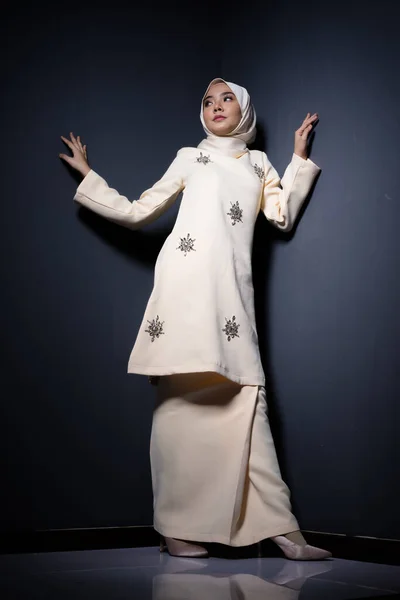 Hijab beauty and fashion editorial concept. A beautiful Muslim model in modern kurung and hijab in various editorial poses for a studio photoshoot. Full length portrait.