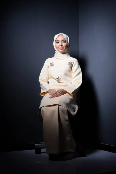 Hijab beauty and fashion editorial concept. A beautiful Muslim model in modern kurung and hijab in various editorial poses for a studio photoshoot. Full length portrait.