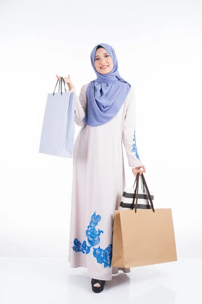 一位漂亮的穆斯林女模特 身穿亚洲传统的朱拜族服装 背着白色背景的购物袋 Eidul Fitri节庆购物概念 全长肖像 — 图库照片
