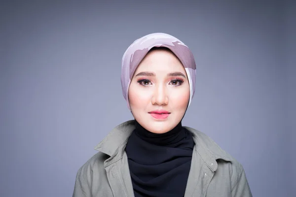 Headshot of a beautiful Muslim female model in a casual wear and hijab isolated on grey background. Hijab fashion and lifestyle portrait concept