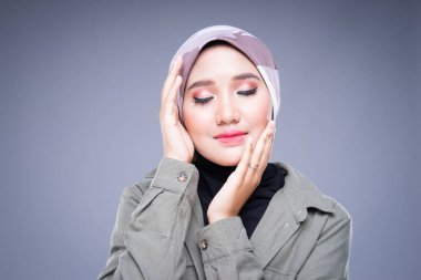 Gri arka planda izole edilmiş günlük kıyafet ve tesettürlü güzel bir müslüman kadın modelin vesikalığı. Türbanlı moda ve yaşam tarzı portresi kavramı