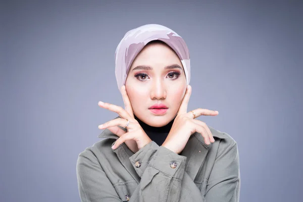 Headshot of a beautiful Muslim female model in a casual wear and hijab isolated on grey background. Hijab fashion and lifestyle portrait concept