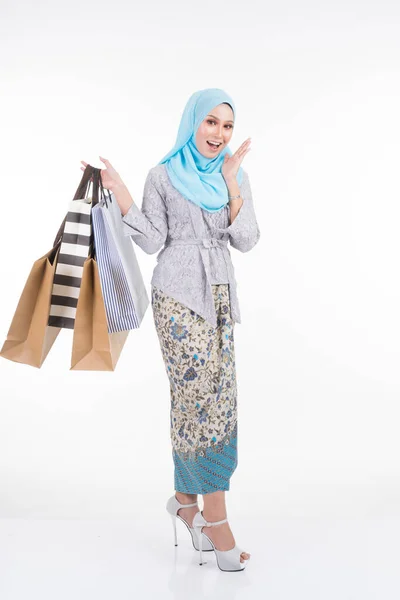 一位漂亮的穆斯林女模特穿着亚洲传统服饰 穿着现代木瓜和头巾 提着白色背景的购物袋 Eidul Fitri时尚和节庆购物理念 — 图库照片