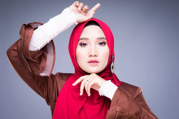 Headshot of a beautiful Muslim female model in an Asian Muslim traditional dress and hijab isolated on grey background. Eidul fitri fashion and lifestyle portrait concept