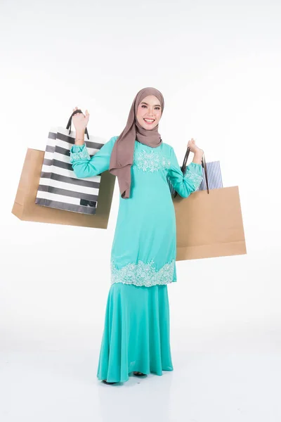 一位美丽而兴奋的穆斯林女模特穿着亚洲传统服饰 穿着时髦的和服 背着白色背景的购物袋 Eidul Fitri节庆准备购物概念 全长肖像 — 图库照片