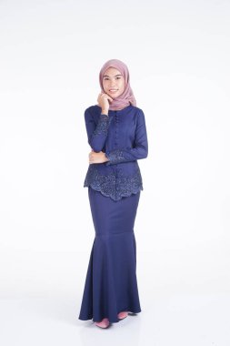 Koyu mavi, tesettürlü bir modern kebaya giyen güzel bir Müslüman kadın model. Beyaz arka planda izole edilmiş Asyalı Müslüman geleneksel bir elbise. Eidul Fitri moda ve yaşam tarzı portresi konsepti.