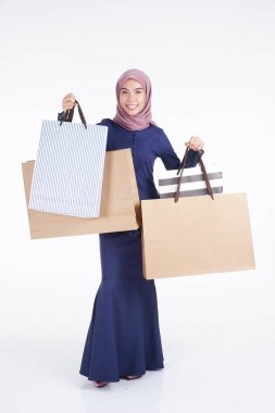 Geleneksel Asya elbisesi içinde güzel ve heyecanlı bir Müslüman kadın model beyaz arka planda izole edilmiş alışveriş torbaları taşıyor. Eidul Fitri moda ve festival hazırlık alışveriş konsepti