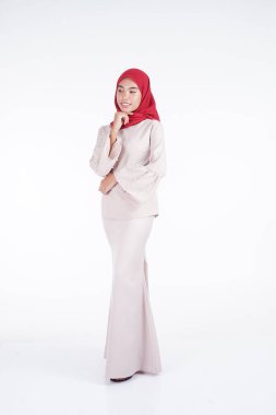 Beyaz arka planda izole edilmiş Asyalı Müslüman geleneksel bir elbise olan kırmızı tesettürlü krem renkli bir modern kebaya giyen çekici Müslüman kadın manken. Eidul Fitri moda ve yaşam tarzı portresi konsepti.