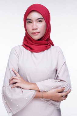 Beyaz arka planda izole edilmiş Asyalı Müslüman geleneksel bir elbise olan kırmızı tesettürlü, krem renkli modern kebaya giymiş güzel bir Müslüman kadın modelin yakın çekimi. Eidul Fitri moda ve yaşam tarzı portresi konsepti.