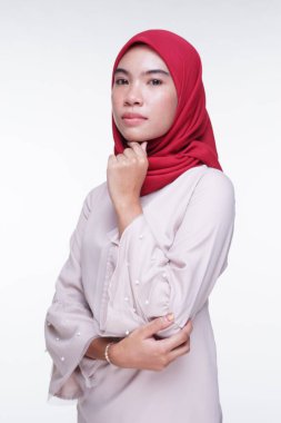 Beyaz arka planda izole edilmiş Asyalı Müslüman geleneksel bir elbise olan kırmızı tesettürlü, krem renkli modern kebaya giymiş güzel bir Müslüman kadın modelin yakın çekimi. Eidul Fitri moda ve yaşam tarzı portresi konsepti.