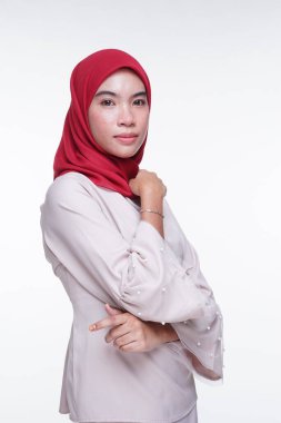 Beyaz arka planda izole edilmiş Asyalı Müslüman geleneksel bir elbise olan kırmızı tesettürlü, krem renkli modern kebaya giymiş güzel bir Müslüman kadın modelin yakın çekimi. Eidul Fitri moda ve yaşam tarzı portresi konsepti.