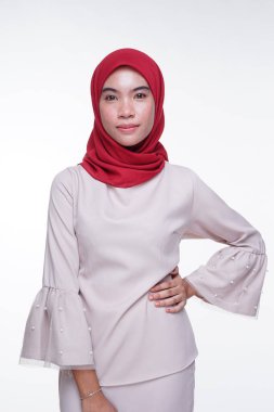 Beyaz arka planda izole edilmiş Asyalı Müslüman geleneksel bir elbise olan kırmızı tesettürlü, krem renkli modern kebaya giymiş güzel bir Müslüman kadın modelin yakın çekimi. Eidul Fitri moda ve yaşam tarzı portresi konsepti.