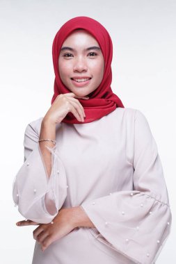 Beyaz arka planda izole edilmiş Asyalı Müslüman geleneksel bir elbise olan kırmızı tesettürlü, krem renkli modern kebaya giymiş güzel bir Müslüman kadın modelin yakın çekimi. Eidul Fitri moda ve yaşam tarzı portresi konsepti.