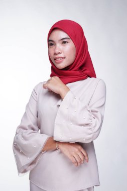 Beyaz arka planda izole edilmiş Asyalı Müslüman geleneksel bir elbise olan kırmızı tesettürlü, krem renkli modern kebaya giymiş güzel bir Müslüman kadın modelin yakın çekimi. Eidul Fitri moda ve yaşam tarzı portresi konsepti.