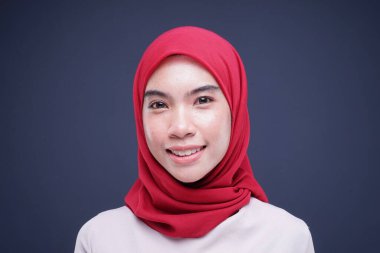 Krem rengi, modern kebaya rengi kırmızı tesettürlü güzel bir Müslüman kadın modelin portresi. Gri arka planda izole edilmiş Asyalı Müslüman geleneksel bir elbise. Eidul Fitri moda ve yaşam tarzı portresi konsepti.